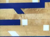 Close-up of a gymnasium floor showcasing various shades of wooden parquet with blue and white painted lines forming geometric patterns across the surface. The lines create a contrast against the wood grain.